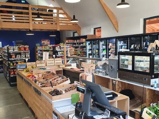 Le comptoir en bois, les fruits et légumes, la vitrine à fromages et la mezzanine sous la charpente