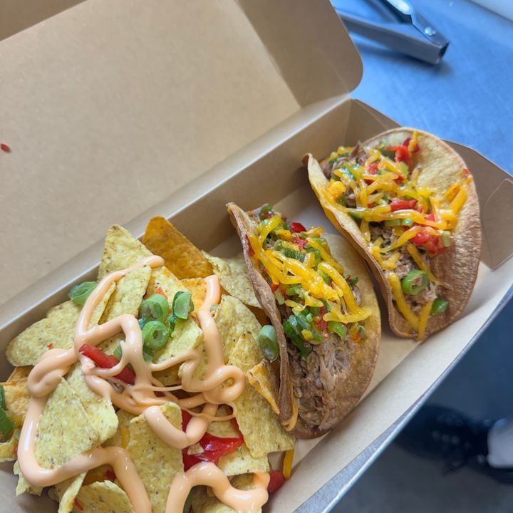 Boîte à emporter avec deux tacos garnis et des nachos